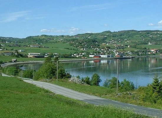 Panoramic view of Leksvik town and fjord from hillside road, showing green agricultural landscape and settlement in Trøndelag, Norway