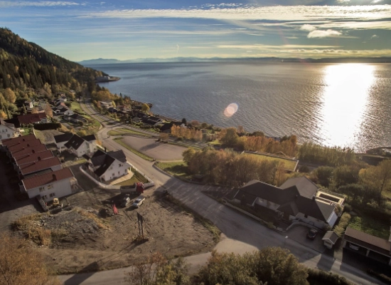 Aerial view of Vanvikan coastal community with residential areas, industrial facilities, and fjord views in golden evening light, Trøndelag, Norway
